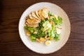 Fresh summer salad Ceasar with eggs, lettuce, chicken and parmesan cheese on white plate on wooden background; healthy concept Royalty Free Stock Photo