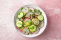 Fresh summer salad with radish, cucumbers, onion, dill and olive oil in a bowl on pink background. Top view Royalty Free Stock Photo