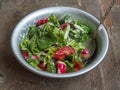 Fresh summer salad of tomatoes, cucumbers and aromatic herbs in a deep bowl with a spoon, with sour cream on an old wooden table Royalty Free Stock Photo