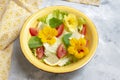 Fresh summer salad with vegetables and edible flowers nasturtium, borage flowers in a yellow bowl. Royalty Free Stock Photo