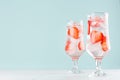 Fresh summer strawberry drink with red fruit pieces, ice cubes, tonic in two glasses light soft pastel  blue color background. Royalty Free Stock Photo
