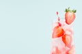 Fresh summer strawberry lemonade with ripe berry pieces, ice cubes, tonic, straw on light soft pastel blue color background. Royalty Free Stock Photo