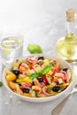 Fresh summer tomato ciabatta salad on the table with fork, lemon water and oil bottle.