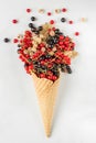 Fresh summer various currant berries in waffle ice cream cone on white marble background. summer food concept. flat lay