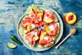 Fresh summer watermelon pizza with feta cheese, peach, prosciutto, jalapeno and honey drizzle on blue background. Royalty Free Stock Photo