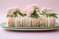 Fresh sushi roll on plate with pink flowers, elegant presentation on pink background Royalty Free Stock Photo