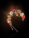 Fresh sushi rolls with chopsticks frozen in the air on a black background Royalty Free Stock Photo