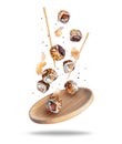 Fresh sushi rolls with ginger falling on a wooden plate isolated on a white background