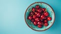 Fresh sweet cherries bowl with leaves in water drops on blue stone background, top view Royalty Free Stock Photo