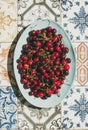 Fresh sweet cherries over oriental ceramic tiles background, top view