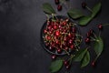 Fresh sweet cherries plate with leaves in water drops on stone background, top view