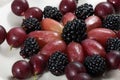 Fresh sweet fruits grapes, blackberries and gooseberries on a light plate