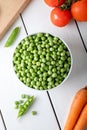 Fresh sweet pea pods. Green peas in white bowl with fresh pods on the white wooden table. Royalty Free Stock Photo