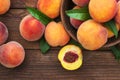 Fresh sweet peaches on the wooden table, selective focus. Fresh ripe peaches with leaves in a bowl on a wooden background Royalty Free Stock Photo