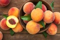 Fresh sweet peaches on the wooden table, selective focus. Fresh ripe peaches with leaves in a bowl on a wooden background Royalty Free Stock Photo