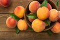 Fresh sweet peaches on the wooden table, selective focus. Fresh ripe peaches with leaves in a bowl on a wooden background Royalty Free Stock Photo