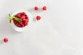 Fresh sweet raspberries in a white cup on white background. Top view, copy space. Natural cosmetics, food background. Summer snack Royalty Free Stock Photo