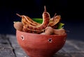 fresh sweet ripe tamarind with leaf, healthy fruit,tamarind fruits and green leaves on red bowl,organic tamarind nature