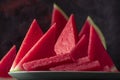 Fresh sweet spanish watermelon sliced on green plate on dark background. Low key close up shot with selective focus Royalty Free Stock Photo