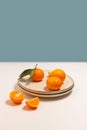Fresh tangerine or clementin fruits on a beige plate with a gold rim on the table. Colorful fruit background. Decorative christmas Royalty Free Stock Photo