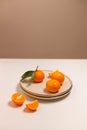 Fresh tangerine or clementin fruits on a beige plate with a gold rim on the table. Colorful fruit background. Decorative christmas Royalty Free Stock Photo