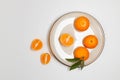 Fresh tangerine or clementin fruits on a beige plate with a gold rim on white background. Colorful fruit background. Flat lay, top Royalty Free Stock Photo