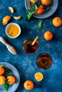 Fresh Tangerines placed on ribbed grey plates with Aperitif in two cocktail glasses over Blue background, top view