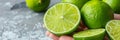 Fresh tangy lime held in hand, assorted limes on blurred background with copy space
