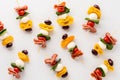 Fresh and tasty antipasto skewers against a white background.