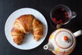 Fresh and tasty bavarian croissant on white plate and a glass of fruit tea over wooden background