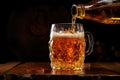 Fresh tasty beer pours from a bottle into a mug on a wooden table in a bar Royalty Free Stock Photo