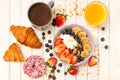 Fresh tasty breakfast with croissant, oat flakes, berries, donuts, coffee and orange Royalty Free Stock Photo