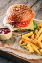 Fresh tasty burger and french fries with sauce on wooden cutting board with wood background Royalty Free Stock Photo