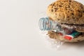 Fresh tasty burger with plastic waste and paper cardboard inside on white background. Recycled waste in our food concept Royalty Free Stock Photo