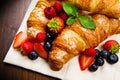 Fresh tasty croissants with berries on wooden background