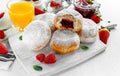 Fresh tasty donuts with ripe berries and raspberries jam on white wooden board.