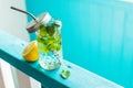 Fresh tasty drink whith lemon and mint in glass on wooden table over turquoise background