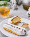 Fresh tasty eclair on white plate and cup of tea Royalty Free Stock Photo