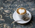 Fresh tasty espresso cup of hot coffee with coffee beans on a blue antique background. Drawing on coffee - heart. Copy space