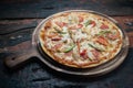 Fresh tasty pizza with chicken, tomato, paprika and mozzarella cheese on rustic wooden background