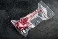 Fresh tasty raw beef Tomahawk steak with bone wrapped in vacuum plastic packing at market, on black stone background, with copy Royalty Free Stock Photo