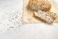 Fresh, tasty, round wheat bread with flax seeds on a white textured table with space for text. Sliced bread on baking paper with Royalty Free Stock Photo