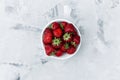 Fresh tasty strawberries in a white plate on a table with a white texture. Top view Royalty Free Stock Photo
