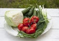 Fresh tasty vegetables from the garden lie on a plate on a table. Cabbage, cucumbers, tomatoes, onions, dill Royalty Free Stock Photo