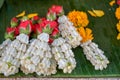 Fresh Thai style flower garlands made of white jasmine, crown flower, red rose and yellow marigold selling on green banana leaves Royalty Free Stock Photo