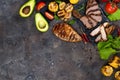 Fresh three types of grilled steak chicken, pork, beef on slate plate with herbs, tomato, avocado and grilled potatoes