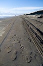 Fresh tire and boot tracks on sand beach near Westport