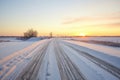 fresh tire tracks on a snowy hill road at sunrise