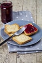 Fresh toasted cereal bread slices on grey plate and jar with homemade cherry jam closeup on linen napkin on rustic wooden table Royalty Free Stock Photo