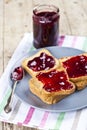 Fresh toasted cereal bread slices with homemade cherry jam in jar and spoon on ceramic plate closeup on linen napkin on rustic Royalty Free Stock Photo